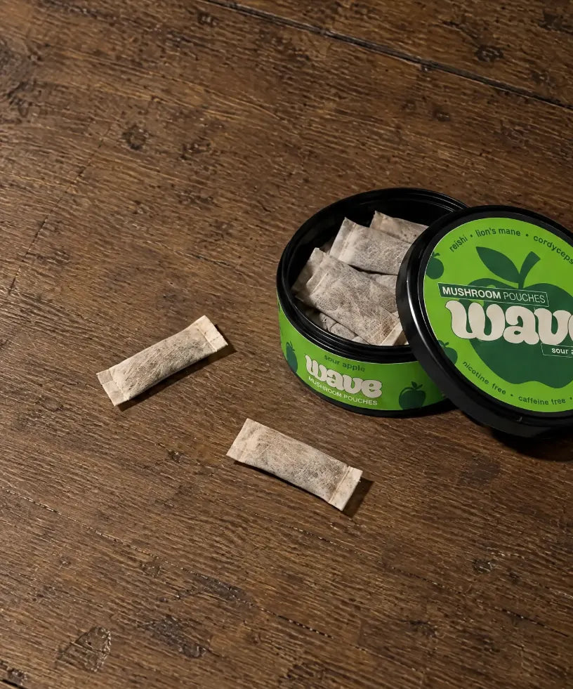 Geöffnete Dose mit WAVE Pouches auf einem Holztisch, daneben zwei Pouches