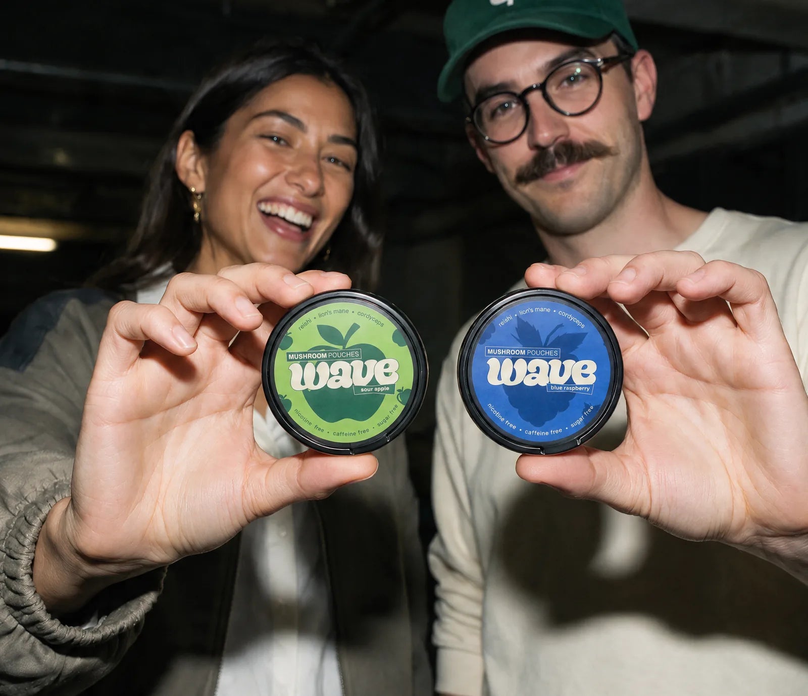 Zwei Freunde in einer Garage halten eine WAVE-Dose Saurer Apfel und eine Blue Raspberry in die Kamera