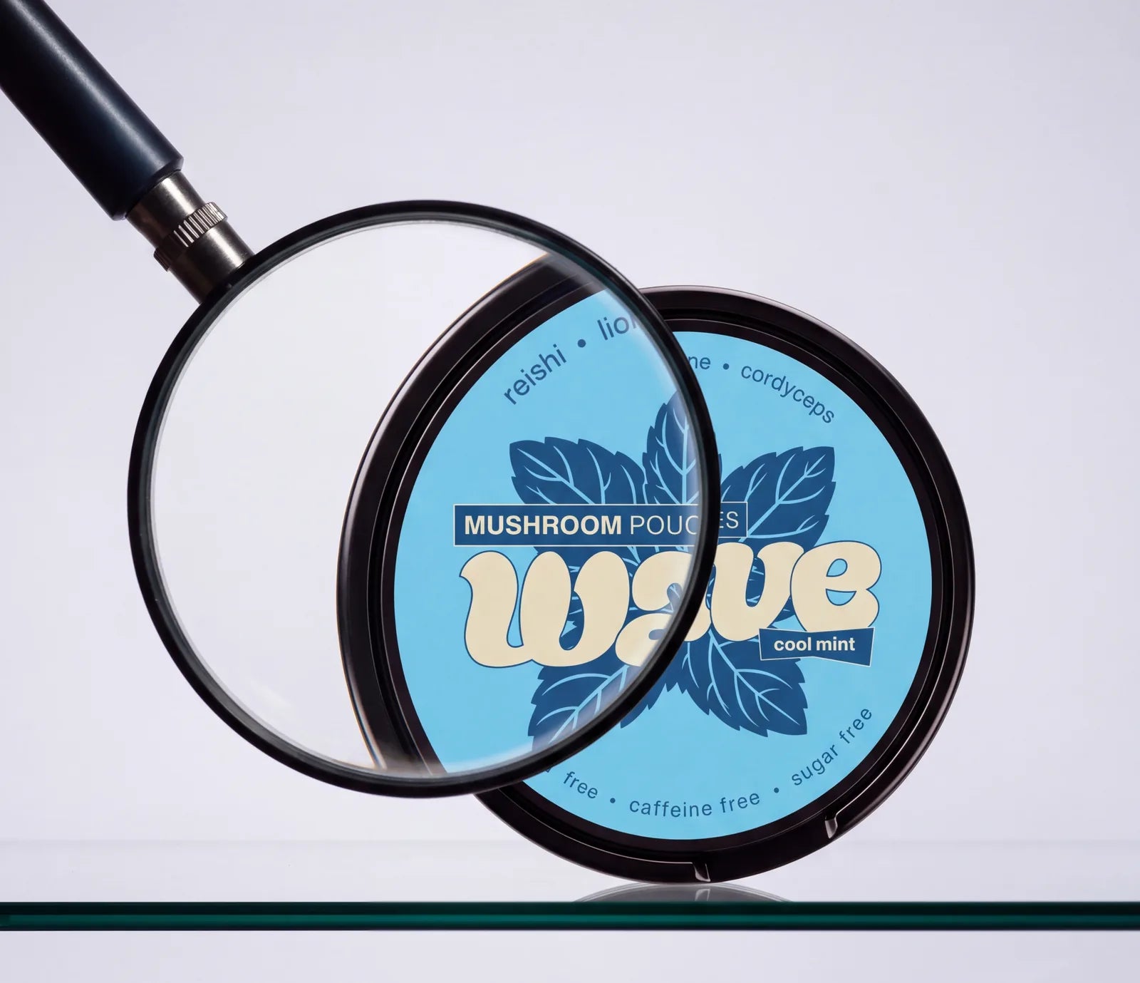 Eine Lupe über einer WAVE-Dose Cool Mint auf einem Glasregal