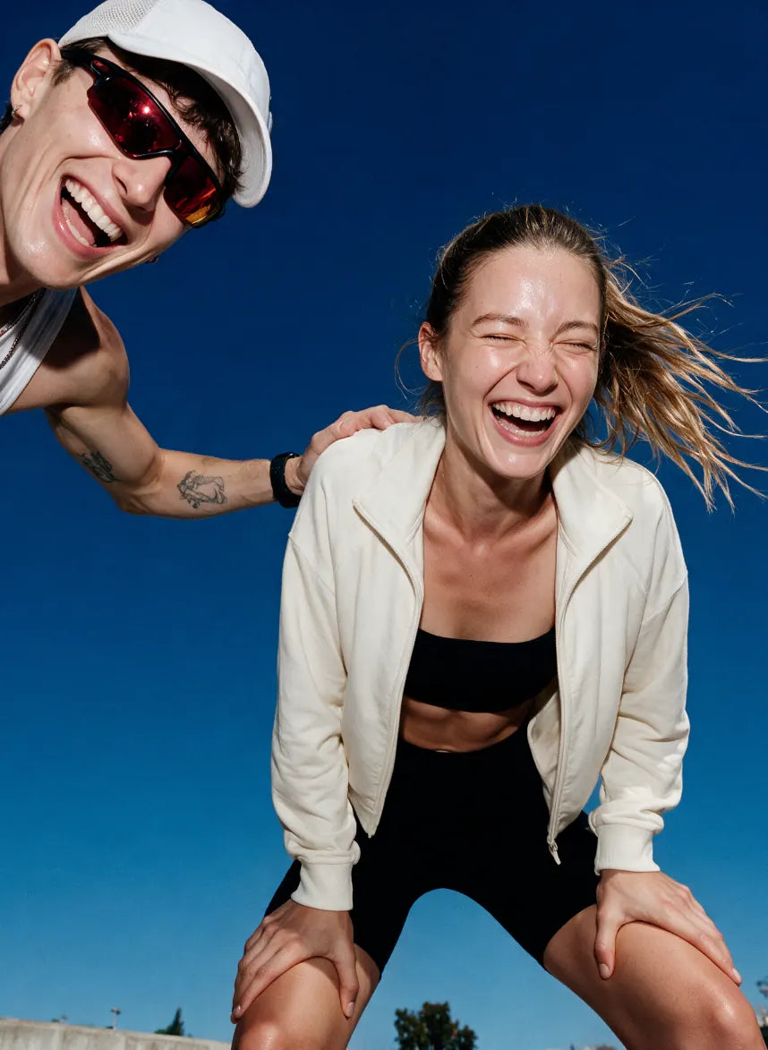 Zwei Freunde lachen draußen unter klarem blauem Himmel