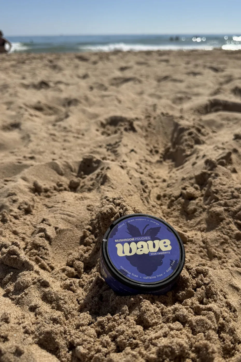 Eine Dose WAVE liegt im Sand am Strand