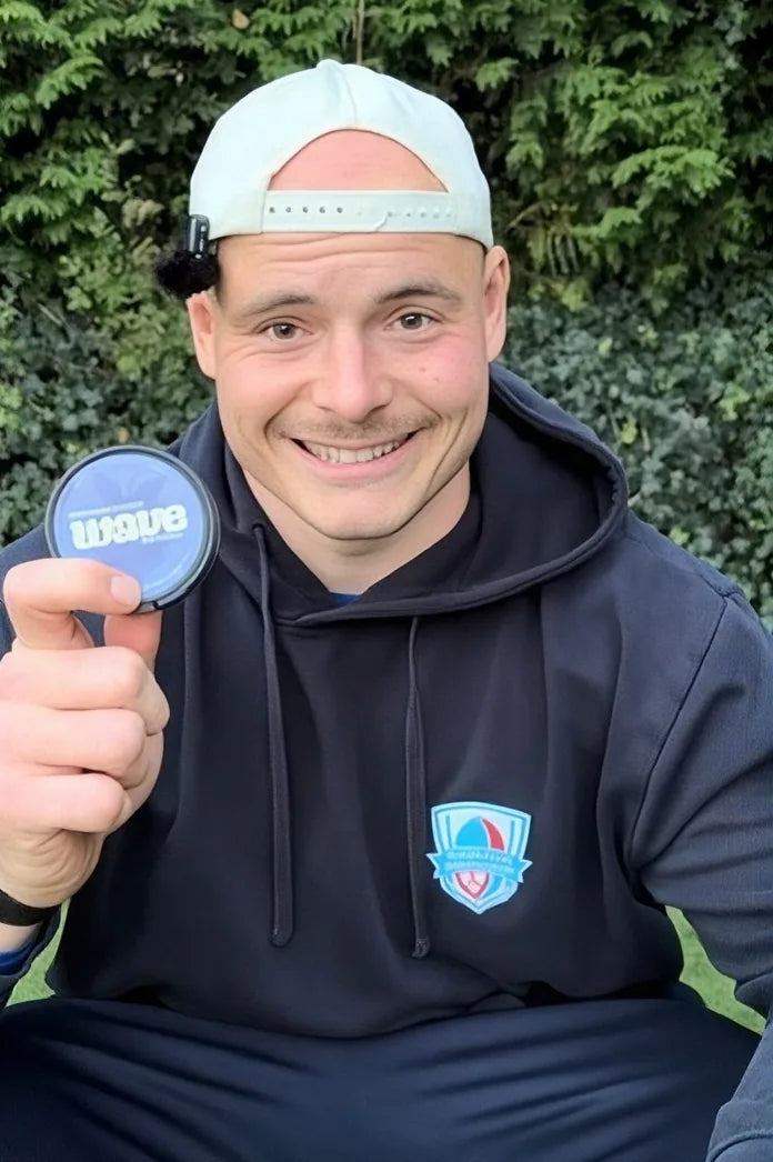 Lächelnder Mann mit weißer Kappe hält eine Dose WAVE hoch
